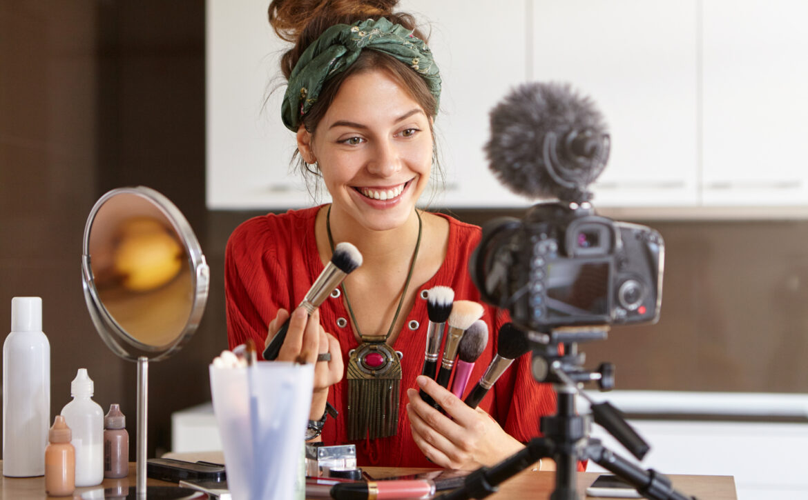 Modern technologies, internet marketing, e-commerce and networking concept. Picture of famous young beauty blogger with charming smile advertising new make up brushes for online beauty store