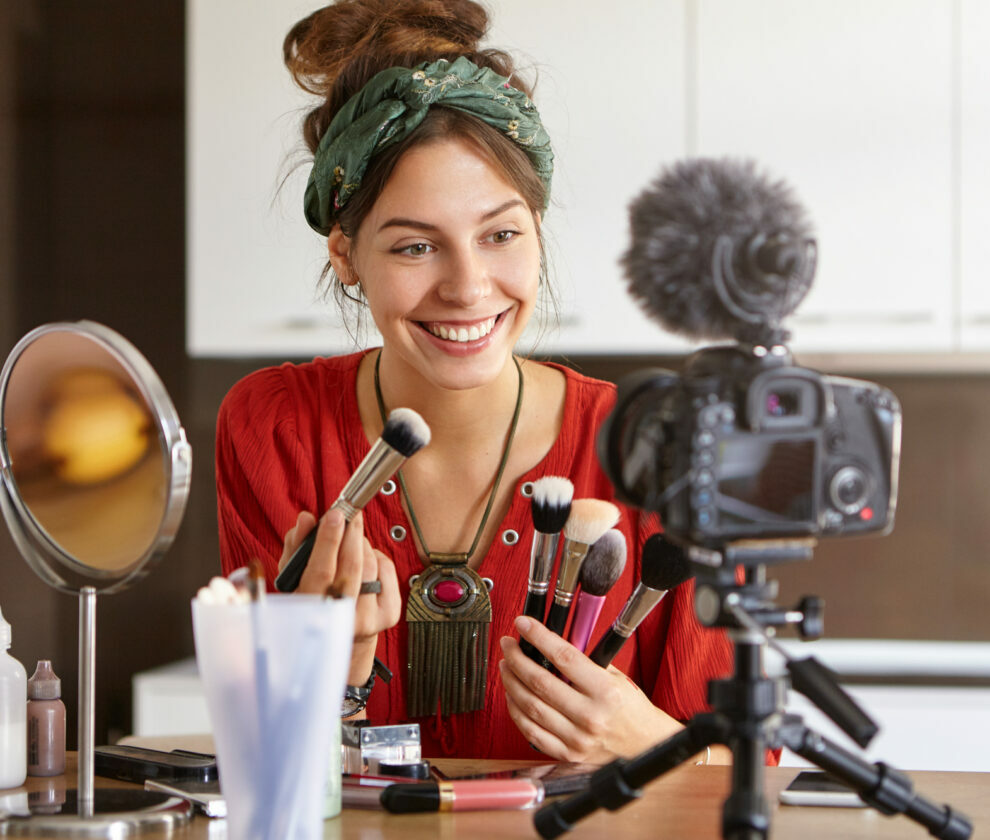 Modern technologies, internet marketing, e-commerce and networking concept. Picture of famous young beauty blogger with charming smile advertising new make up brushes for online beauty store